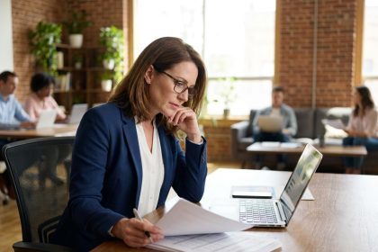 Femme de 40 ans en reconversion professionnelle travaillant sur des documents dans un espace de coworking moderne
